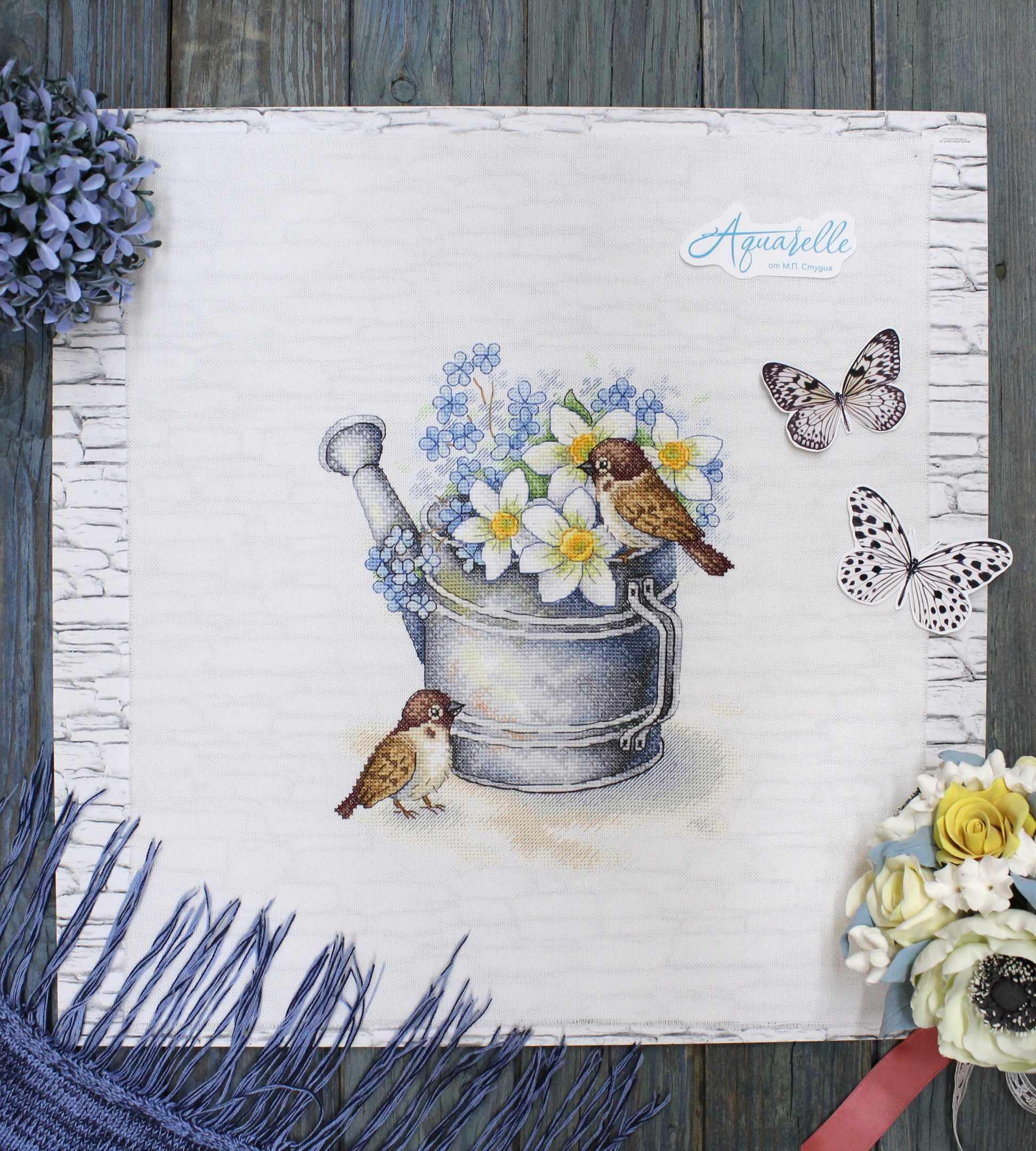 Daffodil Lovers SA-026 Cross-stitch kit featuring a watering can, white chamomiles, blue flowers, and a bullfinch on 27 count canvas.